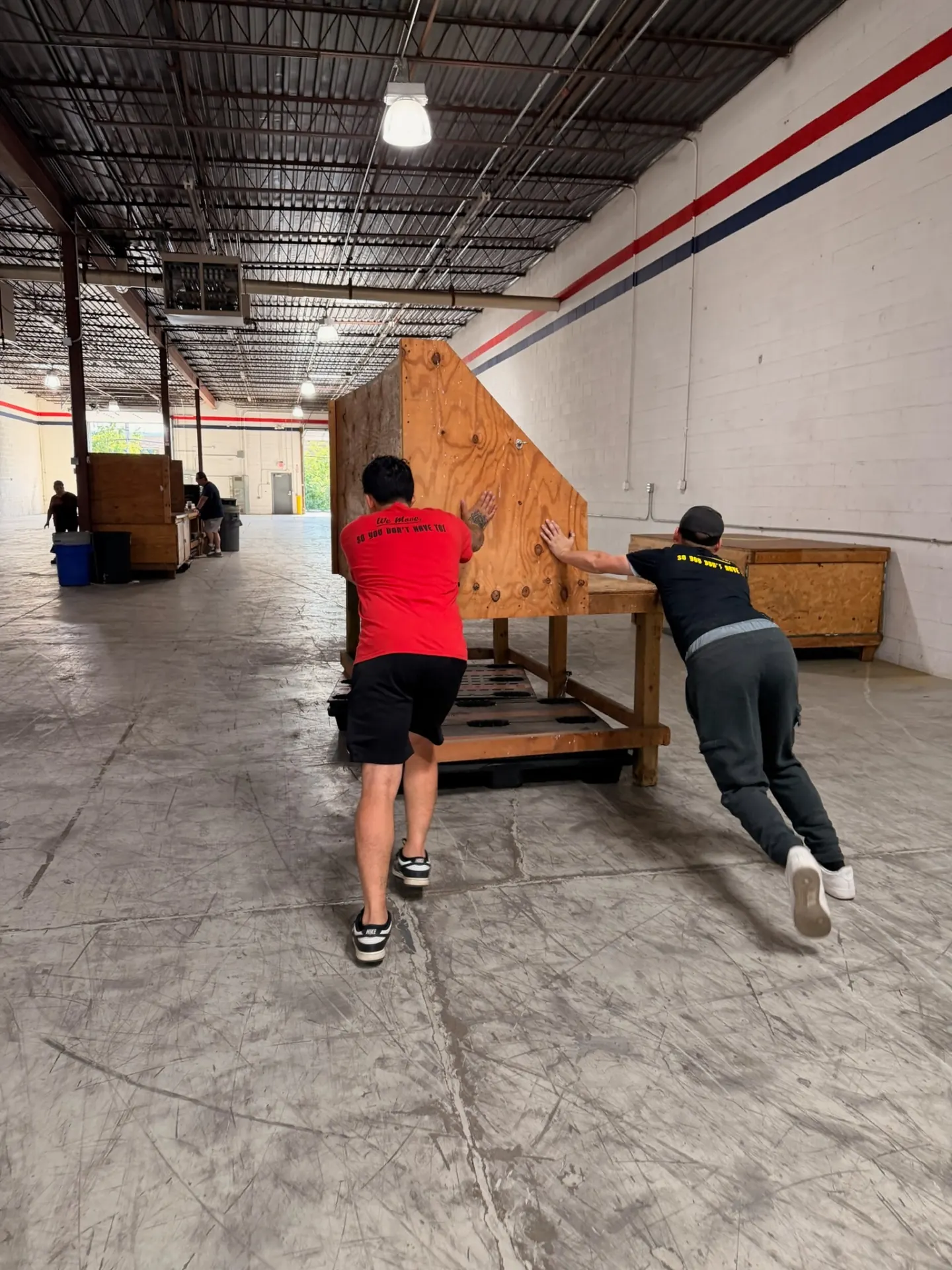 Yellow Truck Moving crew moving a large crated item through a warehouse