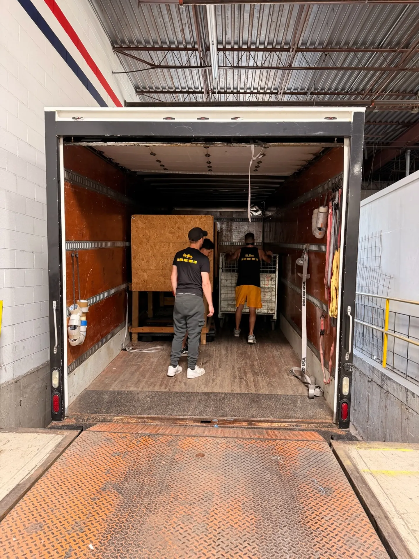 Yellow Truck Moving crew loading equipment into a box truck