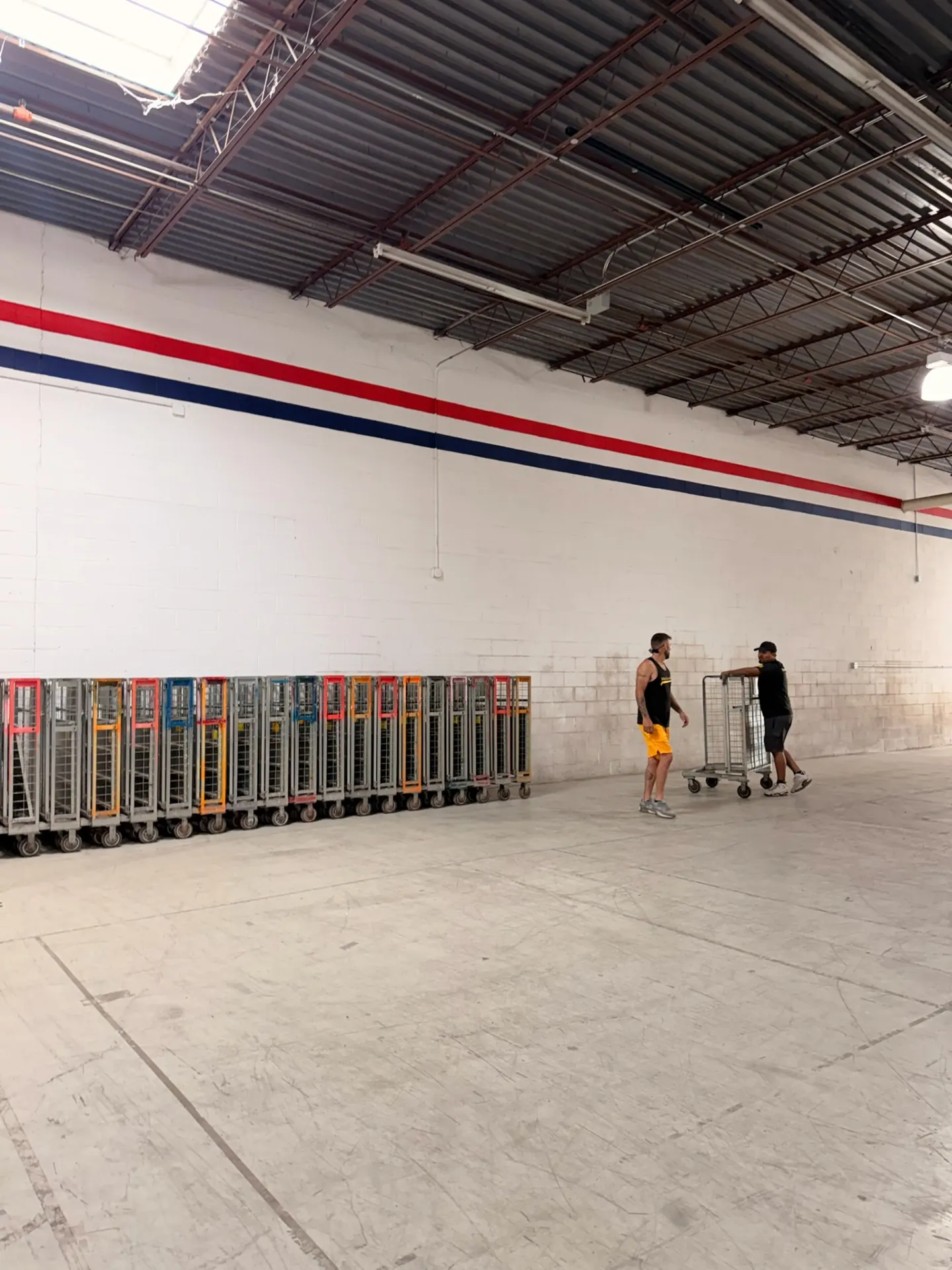 Yellow Truck Moving movers reviewing equipment carts at a warehouse staging area