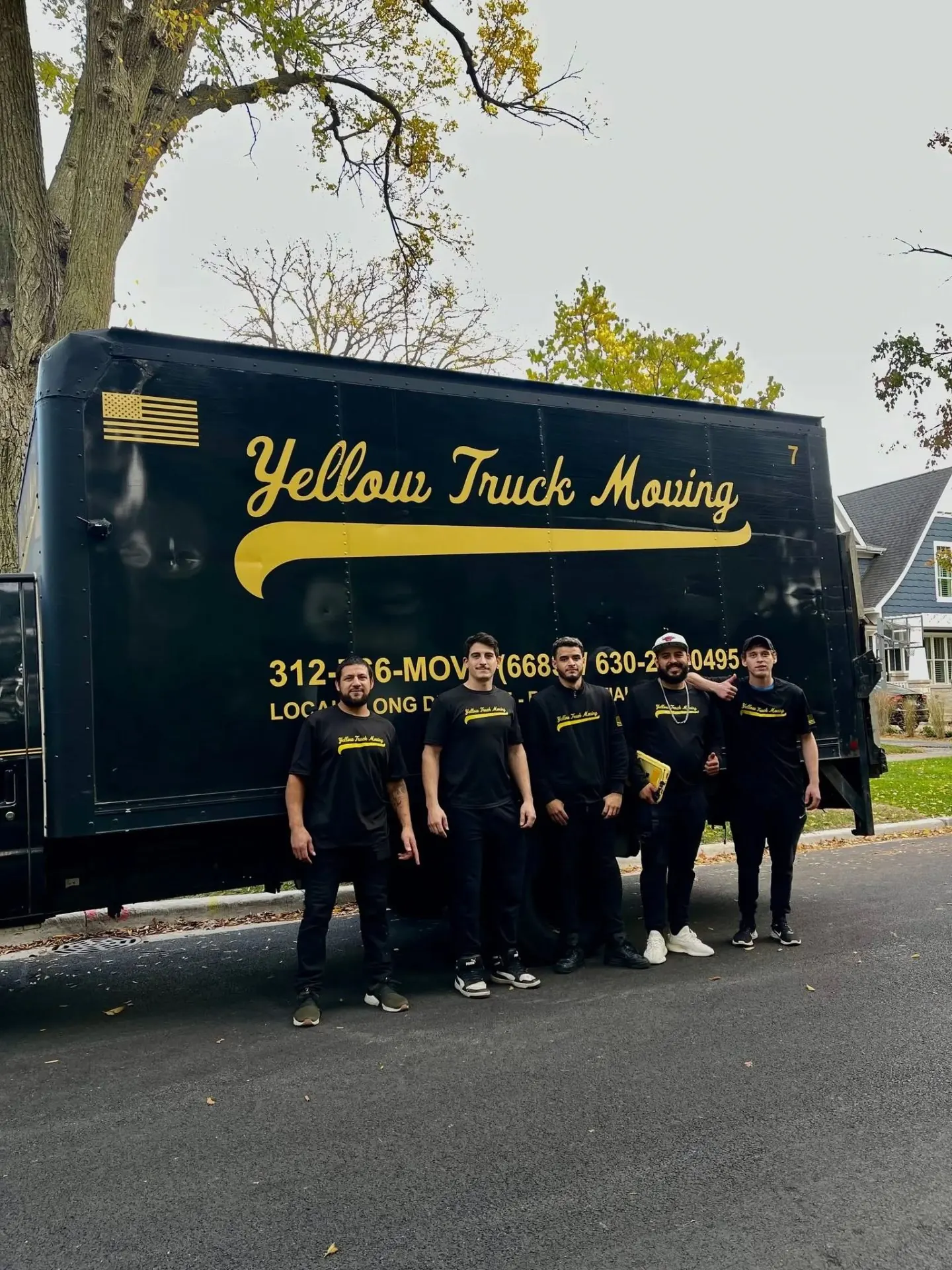 Yellow Truck Moving crew of five standing in front of the black-and-gold branded box truck